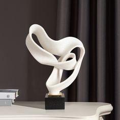 a white sculpture sitting on top of a table next to a book and some books