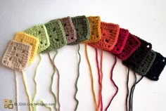 there are many crocheted items on the white wall and one is multicolored