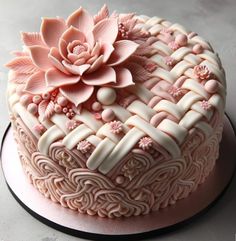 a pink cake with white icing and flowers on top