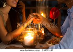 a man and woman sitting at a table holding hands