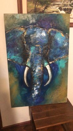 an elephant's head is painted on a canvas in front of a wooden table