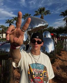 a young man is making the peace sign in front of some shiny balls and palm trees