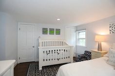 a baby's room with a white crib, dresser and bed in it