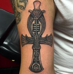 a cross tattoo with an egyptian symbol on it's arm and the word god