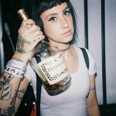 a woman with tattoos holding up a bottle