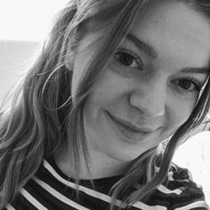 black and white photograph of a woman with long hair smiling at the camera while wearing a striped shirt