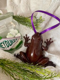 a frog sitting on top of a white blanket next to a jar filled with marshmallows