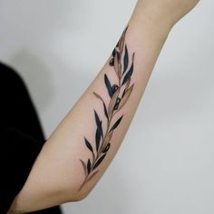 a woman's arm with an olive branch tattoo on it