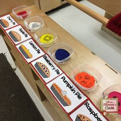 a wooden table topped with lots of plastic containers filled with different colored food and writing