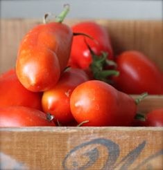 a wooden box filled with lots of red tomatoes