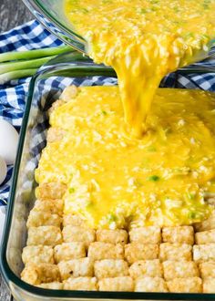 a casserole dish with tater tots and cheese being poured into it