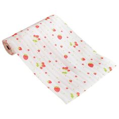 a roll of white fabric with strawberrys and dots on the bottom, in front of a