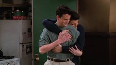 two people hugging each other in a kitchen