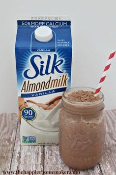 a jar of milk next to a carton of silk almondmik on a wooden table