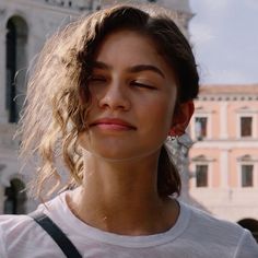 a woman with her eyes closed standing in front of a building