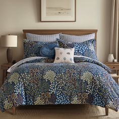 a bed with blue and white comforter in a bedroom next to a lamp on a table