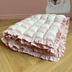 a baby bed with pink ruffles and a white cat on the wall behind it