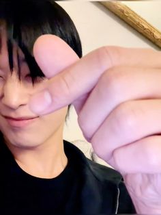 a person with black hair is holding their finger up to the camera and making a face