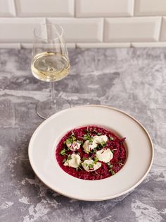 a white plate topped with food next to a glass of wine