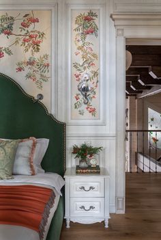 a bedroom with green headboard and floral wallpaper on the walls next to a bed