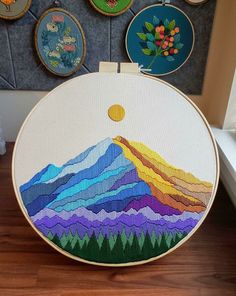 there is a colorful mountain in the middle of this cross stitch pattern on an embroidery hoop