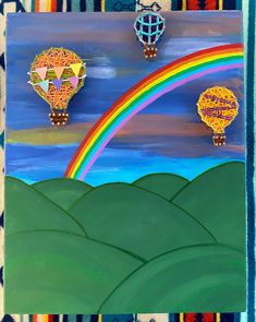 three hot air balloons flying over a rainbow