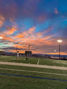 people are playing soccer on the field at sunset