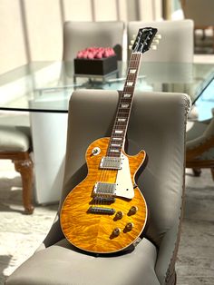 an electric guitar sitting on top of a chair in front of a glass dining table