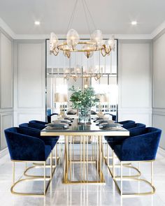 an elegant dining room with blue chairs and a chandelier