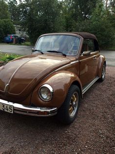 a brown car parked on top of a gravel road