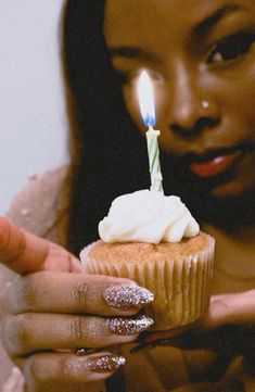 a woman holding a cupcake with a candle in it