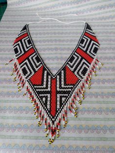 a beaded necklace with beads and tassels on top of a striped table cloth