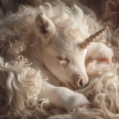 a white unicorn laying on top of a pile of fluffy fur with its eyes closed