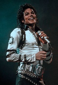 michael jackson singing into a microphone with his hand on his hip and wearing an elvis costume