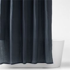 a black shower curtain with a white tub in front of it on a white floor