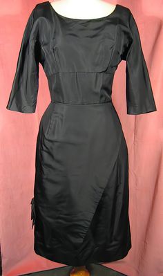 "Elegant 1950s LBD in black silk faille by Miss Brooks. Very well made with an interesting bowed overskirt, it's about a size 10. It measures approx. up to 41\" bust, 29\" waist, 41\" hips, 17\" waist length, and 26 1/2\" skirt length. Excellent condition. See my entire shop collection here https://www.etsy.com/shop/RobinClaytonVintage" Retro Black Vintage Dress For Evening, Black 1950s Style Wedding Dress, Retro Formal Dress In Solid Color, Black Dress With Fitted Bodice For Vintage Events, Retro Black Wedding Dress, 1950s Style Black Cocktail Dress, Black 1950s Style Cocktail Dress, Vintage Solid Color Formal Dress, Formal Fitted Vintage Dress