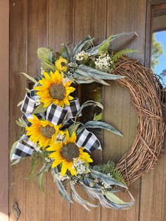 a wreath with sunflowers and greenery hangs on a door