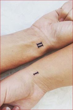 two people with matching tattoos on their arms, one is holding the other's hand