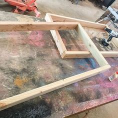 some wood is laying on top of a table with paint and other items around it