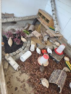 an outdoor garden area with rocks, gravel and plants on the ground in front of a white wall