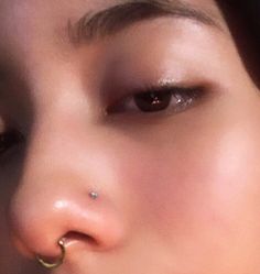 a close up of a woman with piercings on her nose and nose ring in front of her face