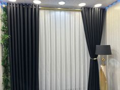 a living room with black and white drapes on the wall, gold lamp in the corner