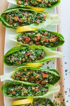 four lettuce boats filled with pesto sauce on top of a white plate