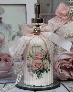 a white bell with pink roses and pearls on the top is sitting in front of some flowers