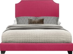 a bed with a pink upholstered headboard and two pillows on top of it