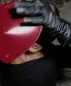 a woman in black gloves holding a red heart