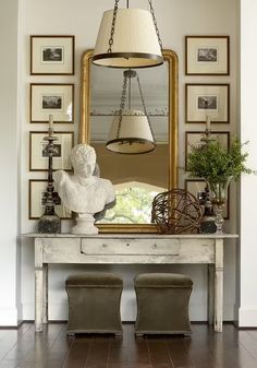 a white table topped with a mirror next to a lamp and two stools in front of it