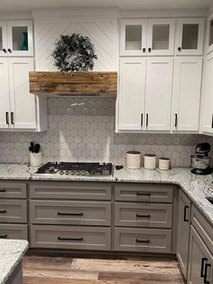 a kitchen with white cabinets and gray counter tops