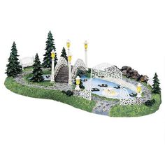 a miniature model of a bridge over a pond with trees and lights on the sides