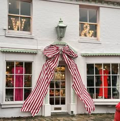 a red and white striped bow on the side of a building with windows in front of it